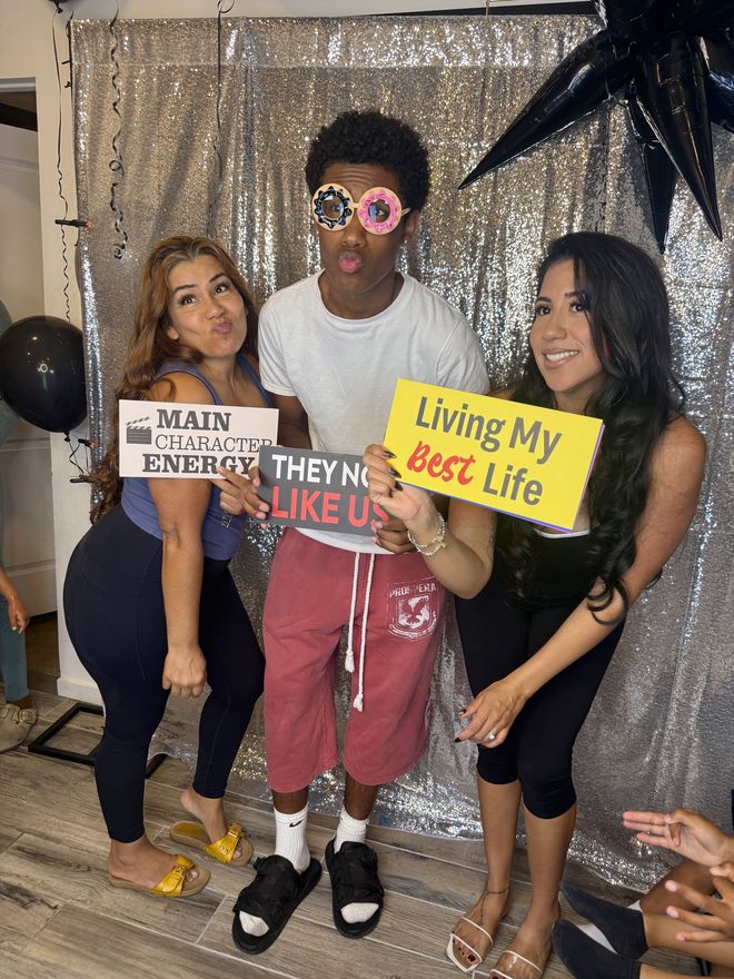 Three guests posing with Main Character Energy and Living My Best Life signs